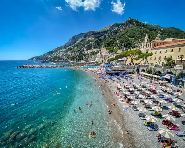 Spiaggia affollata con ombrelloni e gente che nuota, un'ottima idea per un weekend in Italia con vista sulla costa.