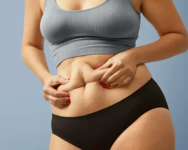 Kobieta z widocznym fałdem tłuszczu na brzuchu, mimo szczupłej sylwetki. Zjawisko "skinny fat" w praktyce.