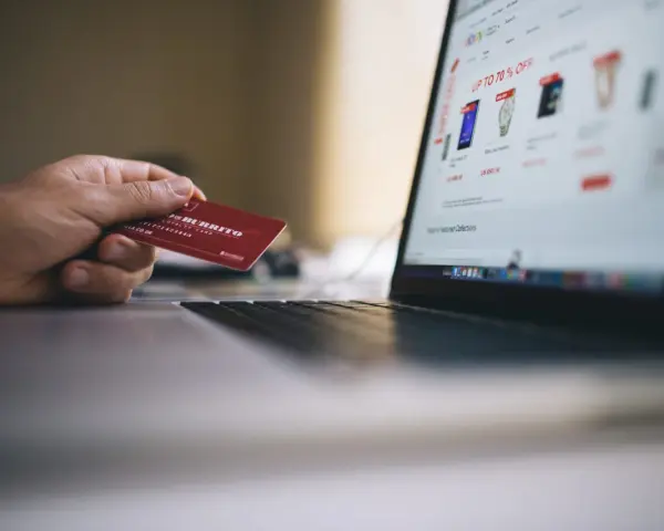 Dłoń trzyma kartę lojalnościową, przygotowując się do zakupów online. Może to być import z Wielkiej Brytanii, np. z sieci sklepów.