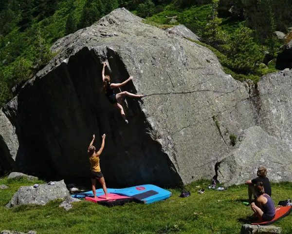 Zwei Frauen klettern an einem Felsen, eine oben, die andere unten. Das ist, was ist bouldern: Klettern ohne Seil an niedrigen Felsen.