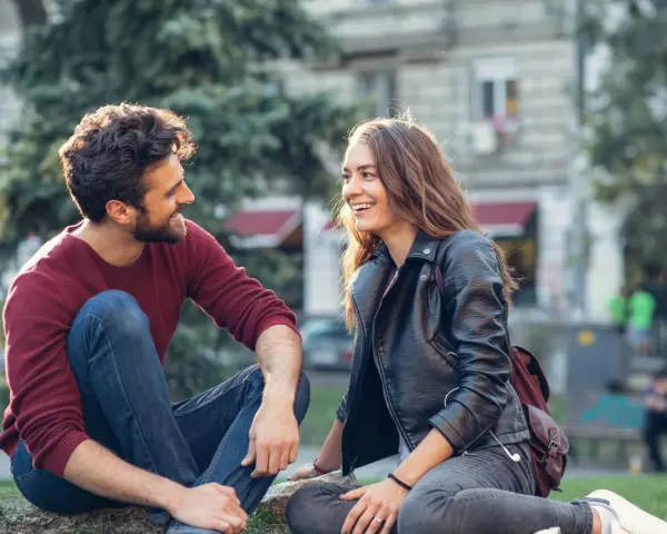 Un couple rit en s'asseyant dehors. Un moment complice pour montrer à son partenaire qu'on a envie de lui.