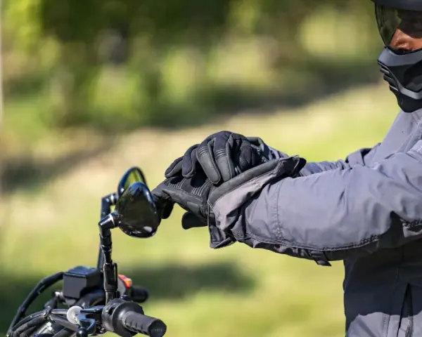 Motociclista con casco integrale obbligatorio e guanti neri, pronto per un viaggio su strada.