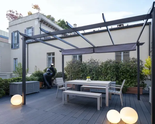 Terrazze arredate con tavolo, panche, sedie e scultura di gorilla sotto una pergola. Illuminazione soffusa con sfere luminose.