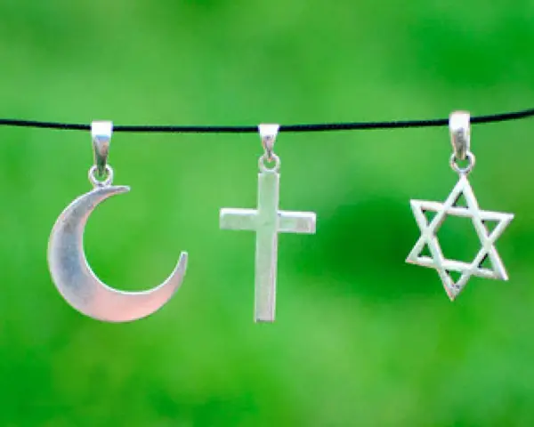 Srebrny półksiężyc, krzyż i gwiazda Dawida wiszą obok siebie. Symbolika islamu, chrześcijaństwa i judaizmu w harmonii.