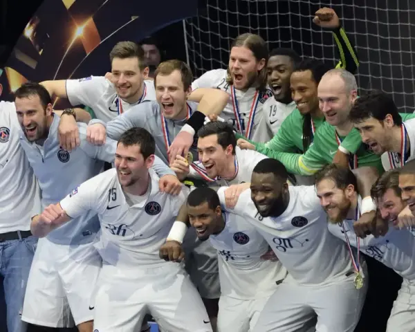 Drużyna PSG Handball świętuje zwycięstwo, otoczona kibicami.