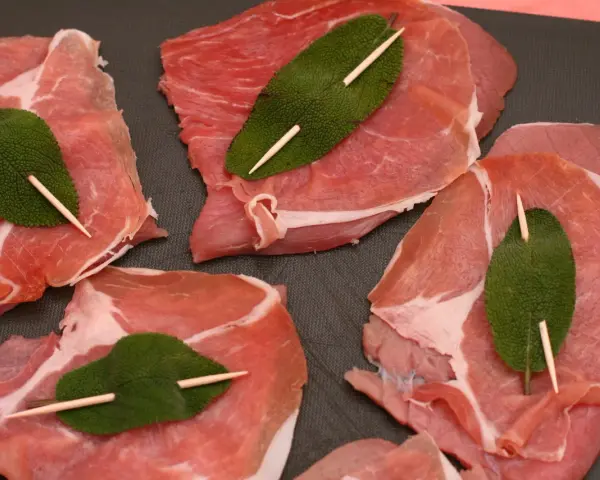 Fette di vitello pronte per la saltimbocca alla romana ricetta originale, con prosciutto crudo e foglie di salvia fissate con stuzzicadenti.