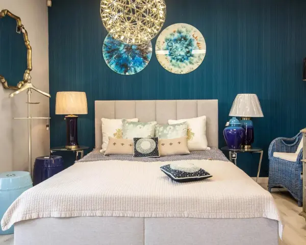 Złote, ozdobne lustro w sypialni feng shui odbija niebieską ścianę i dekoracje.