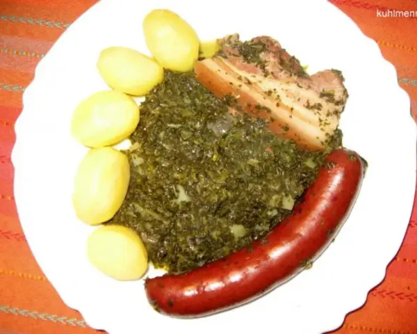 Gedünsteter Grünkohl mit Salzkartoffeln, Kassler und einer herzhaften Lungenwurst, die zum Kochen oder Braten bereit ist.