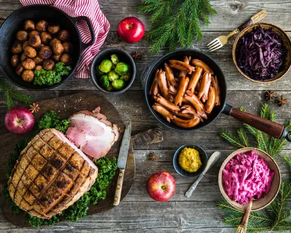 Här är en härlig bild som visar vad som finns på julbordet: köttbullar, prinskorv, julskinka, rödkål, brysselkål och äpplen.