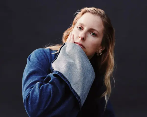 Susanne Sundfør w dżinsowej kurtce, z dłonią na policzku, jakby inspirowana utworem "Blómi".