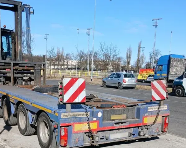 Ciężarówka z naczepą przewozi wózek widłowy. To przykład pojazdu nienormatywnego, który wymaga specjalnych zezwoleń.