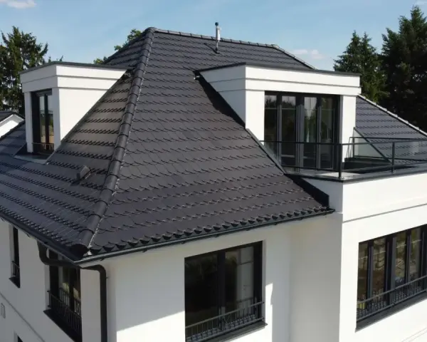 Modernes Haus mit dunkler Dachbeschichtung. Mögliche Nachteile der Dachbeschichtung: Hitzestau im Sommer, höhere Kosten bei Reparaturen.