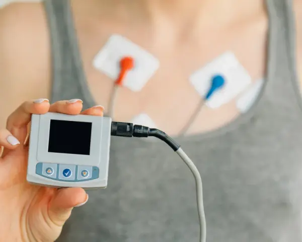 Holter co to? Urządzenie do monitorowania pracy serca z elektrodami na klatce piersiowej i małym rejestratorem w dłoni.