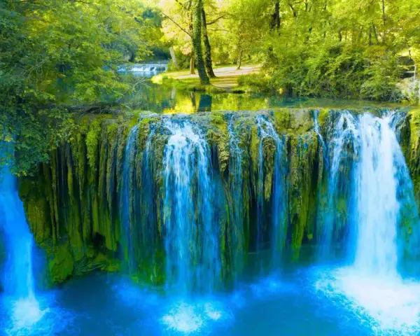 Cascata rigogliosa in Toscana, ideale per escursioni nella natura. Acqua cristallina e vegetazione lussureggiante creano uno scenario incantevole.