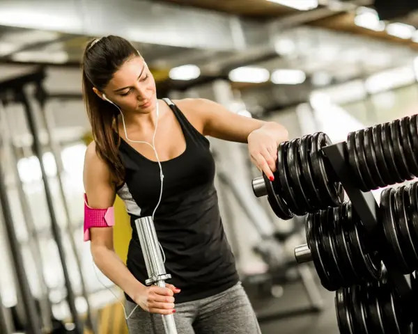 Kvinna väljer vikter på gymmet, bra gym tips för din träning.