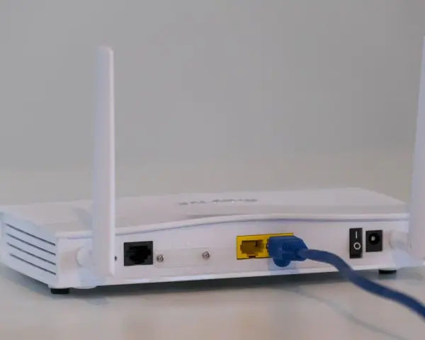 Biały modem z dwiema antenkami, podłączony niebieskim kablem Ethernet. To urządzenie, które pozwala na połączenie z internetem.