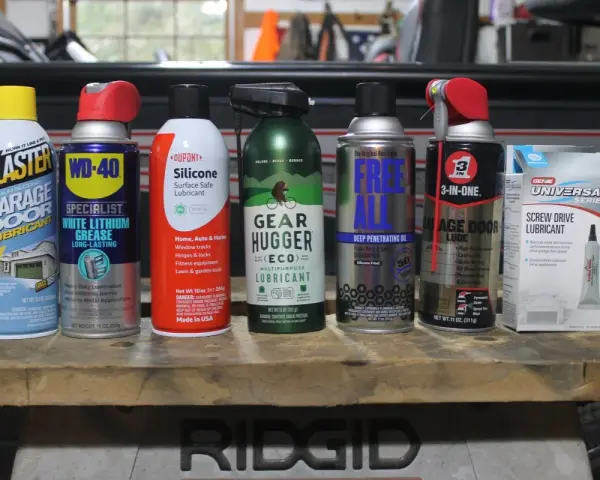 A collection of garage door lube and other lubricants, including Blaster, WD-40, Dupont Silicone, Gear Hugger, Free All, 3-in-One, and Genie Screw Drive Lubricant.