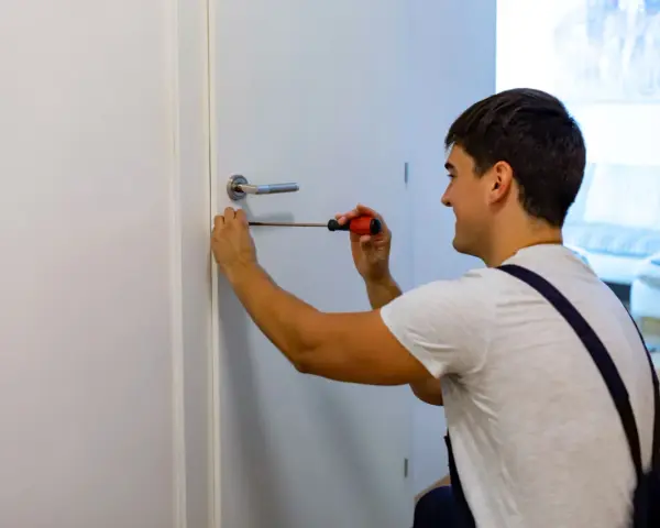 Hombre arregla manija de puerta con destornillador. Podría estar a punto de cambiar marco puerta.