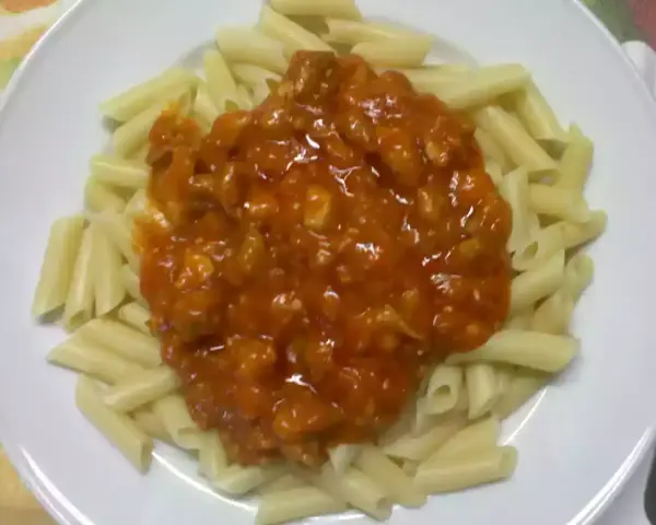 Macarrones con pollo en salsa roja, un plato casero listo para disfrutar.