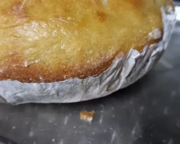 Goldbrauner Teig klebt am Backpapier, das auf einem Metallblech liegt. Ein Teil des Teigs ist bereits abgelöst.