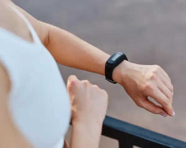 Kobieta sprawdza na swoim nadgarstku, co to jest smartband, monitorując aktywność fizyczną.