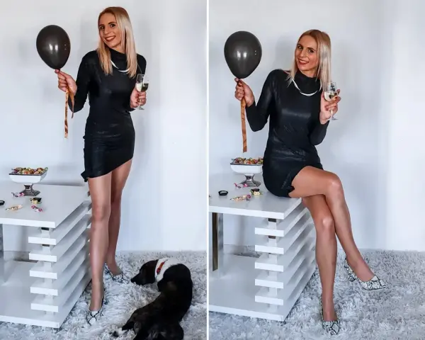 Elegancka czarna sukienka, idealna na 18. urodziny. W dłoni czarny balon i kieliszek szampana. Na podłodze leży piesek.