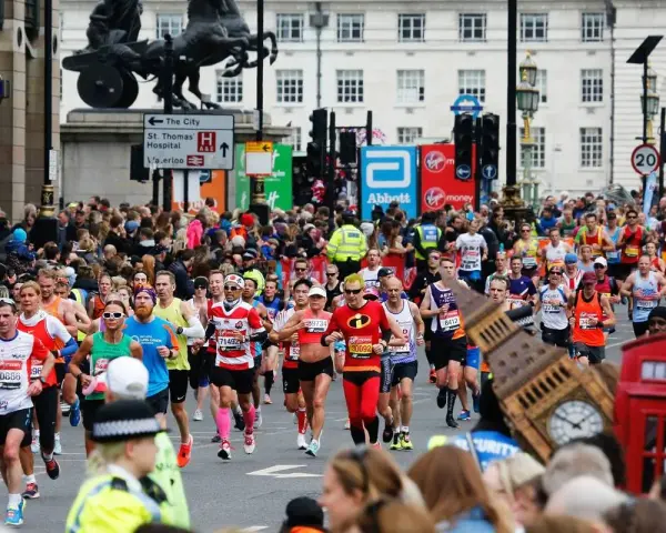 Corredores participan en el maratón de Londres, con Big Ben y cabinas telefónicas rojas de fondo.