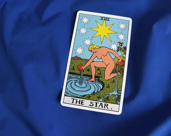 Karta XVII - Gwiazda Tarot. Kobieta wylewa wodę z dzbanów do stawu, symbolizując nadzieję i odnowę.