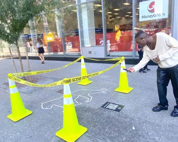 Ein Mann scannt mit seinem Handy einen QR-Code neben einer Kreideumriss-Leiche. Ein cleveres Guerilla-Marketing-Event.