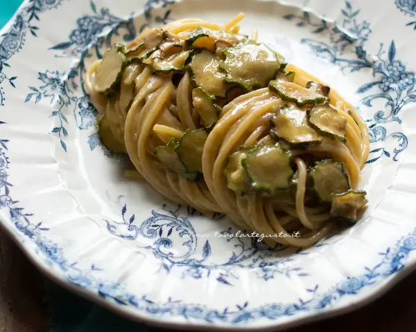 Un piatto di spaghetti alla nerano ricetta, conditi con zucchine saltate e una cremosa salsa al formaggio, serviti su un piatto decorato.