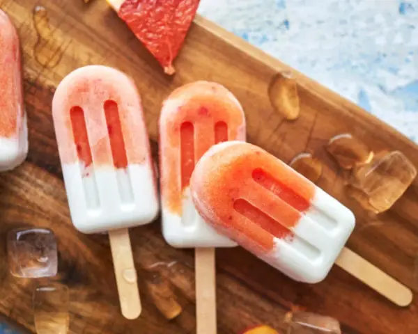 Erfrischendes Erdbeereis auf Holzbrett, mit Eiswürfeln und Grapefruitstücken. Perfekt für heiße Tage, wenn man Kalorien im Blick behält.