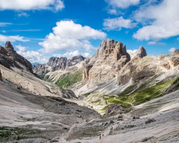 Malownicze **Val di Fassa** w Dolomitach. Kręta ścieżka prowadzi przez skaliste zbocza i zielone hale ku majestatycznym szczytom.