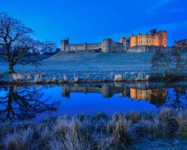 Un château majestueux se reflète dans l'eau calme, sous un ciel d'un bleu profond. Une scène paisible de **heure bleue photo**.