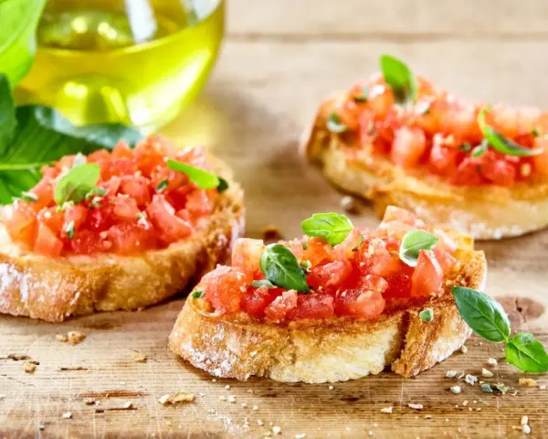 Bruschetta z pomidorami i mozzarellą – pyszny przepis na letnią przekąskę. Chrupiące grzanki z soczystymi pomidorami i świeżą bazylią.