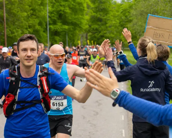 Glada löpare ger high-fives under loppet. Sista veckan innan halvmarathon, peppas deltagarna av publiken.