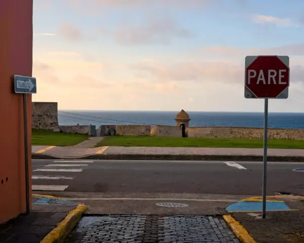 A "PARE" sign stands by the ocean in Puerto Rico. Should I rent a car to explore this beautiful island?