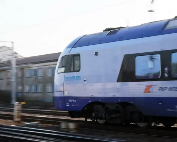 Pociąg PKP Intercity Stadler ED160-007 mija budynek. Może to być widok podczas przebukowania biletu na podróż.
