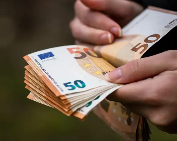 Dłonie trzymają stos banknotów 50 euro. Choć Bułgaria ma swoją walutę, euro jest powszechnie akceptowane.