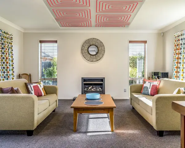 Sala de estar con sofás, chimenea y un moderno techo radiante con patrón de espiral roja.