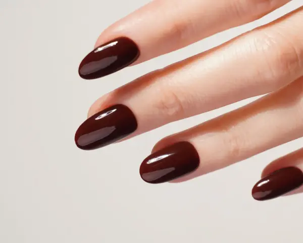 Une idée manucure automne : des ongles courts et arrondis, vernis d'un brun chocolat profond et brillant, évoquant la douceur des feuilles mortes.