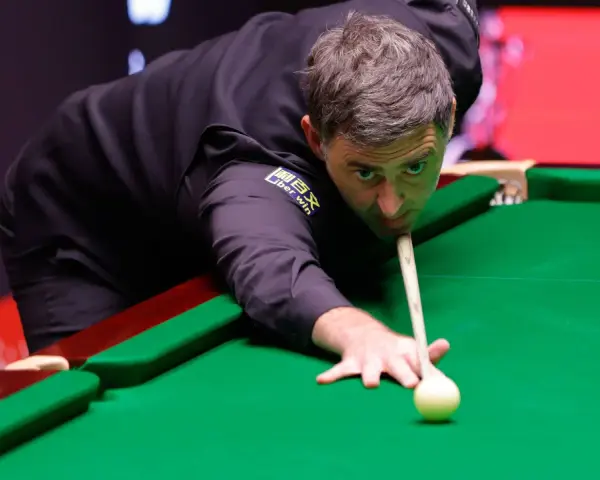 Ronnie O'Sullivan, jeden z najlepsi snookerzyści wszechczasów, skupiony przy zielonym suknie, celuje w bilę.