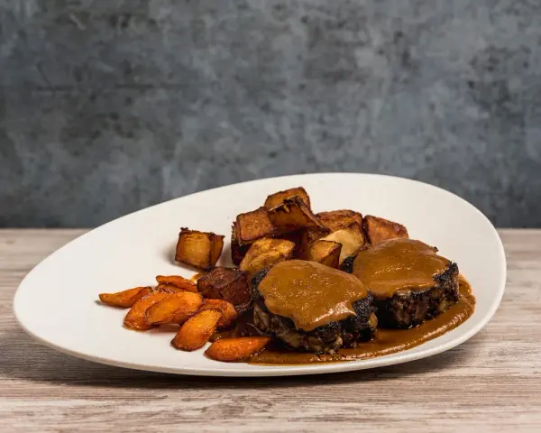 Delicioso rabo de toro bañado en salsa, acompañado de patatas rústicas y zanahorias glaseadas.