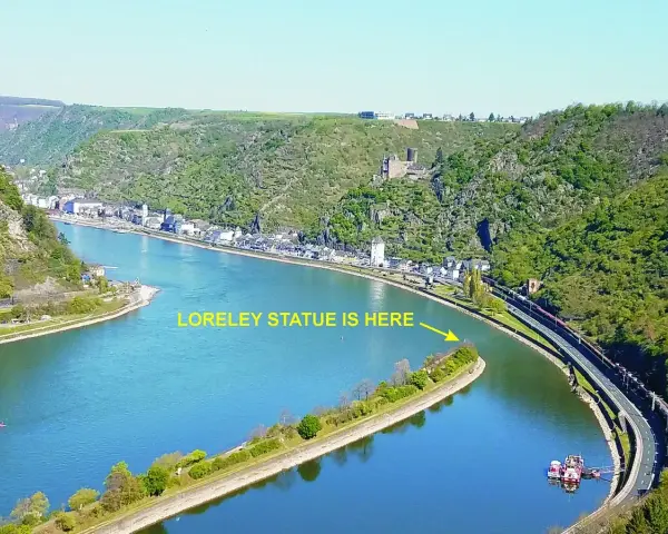 En vidsträckt vy över Loreleis flod, med en stad längs stranden och en järnväg som löper längs floden.