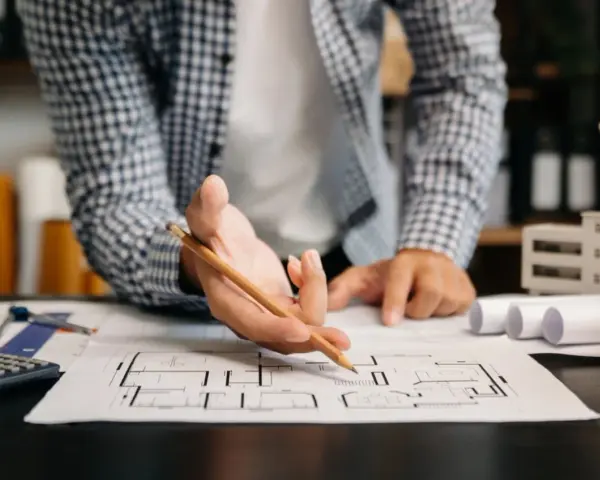 Architekt analizuje plany mieszkania, zastanawiając się, dlaczego od 2026 roku każde mieszkanie na sprzedaż musi mieć audyt akustyczny.