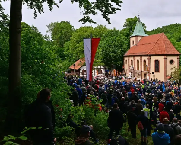 Große Menschenmenge versammelt sich vor einer Kirche zu Christi Himmelfahrt. Fahnen wehen, ein Gottesdienst findet statt, inspiriert von der Bibel.