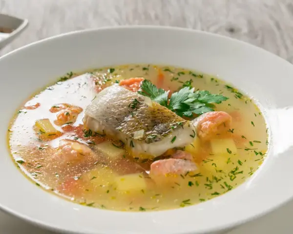 Aromatyczna zupa rybna, przepis babci, z kawałkami ryby, ziemniakami i marchewką, ozdobiona natką pietruszki.