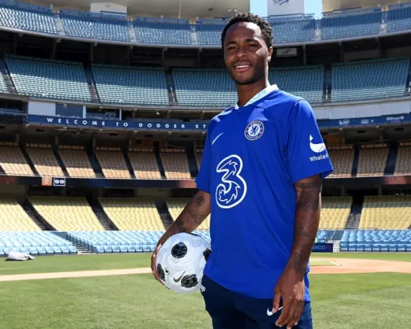 Raheem Sterling w niebieskiej koszulce Chelsea z piłką, na tle stadionu. Jego statystyki w klubie są obiecujące.