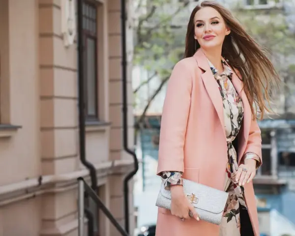 Donna con cappotto rosa e abito floreale, perfetta idea su come vestirsi per una comunione.