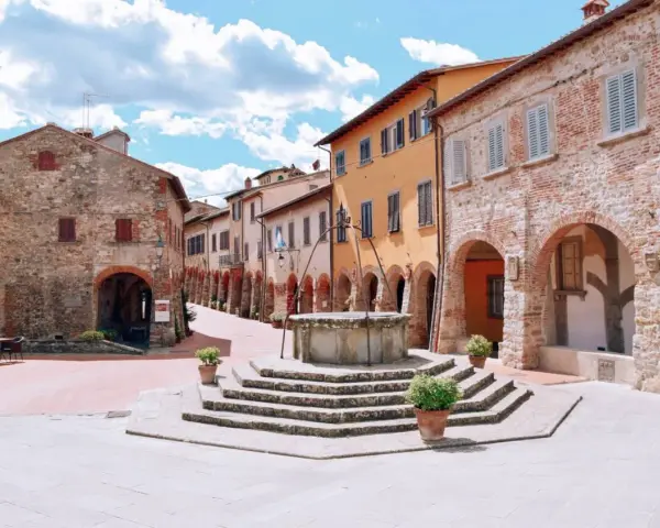 Piazza con pozzo antico e case in pietra e intonaco colorato, un assaggio di cosa vedere a Civitella in Val di Chiana.