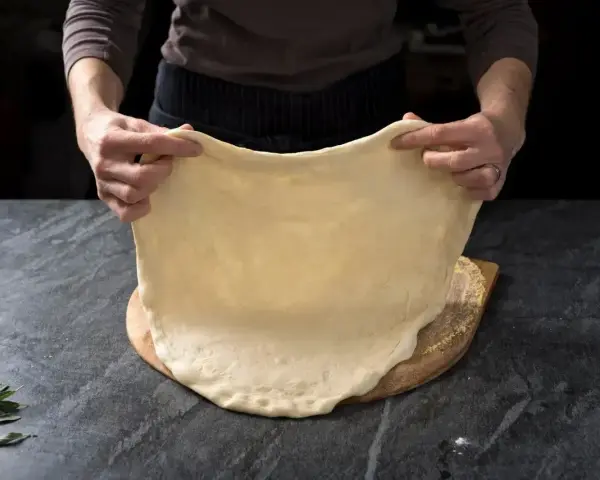 Rozciąganie elastycznego ciasta na pizzę, idealnego do szybkiego przepisu na ciasto do pizzy.